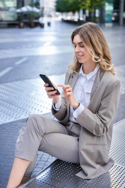 vertical-portrait-businesswoman-suit-using-her-phone-relaxing-outdoors-sitting-bench